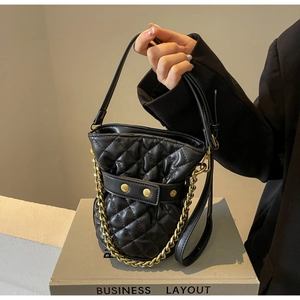 Close-up of black quilted leather bucket bag with gold chain strap and metal clasp detail