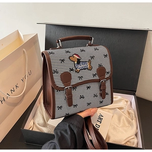 Detail of retro houndstooth backpack with dog embroidery and brown leather trim in gift box