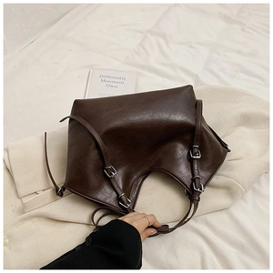 Close-up of a deep brown faux leather tote bag with silver buckles and textured finish