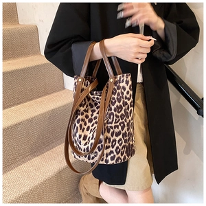 Close-up of leopard print bucket bag with brown leather handles and gold metal hardware