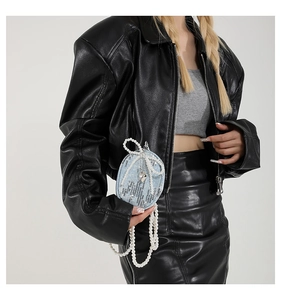 Détail du mini sac en denim bleu avec paillettes, nœud en perles et pendentif cœur sur modèle