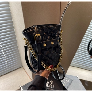 Detail of black quilted leather bucket bag with gold chain and metal rivets decoration