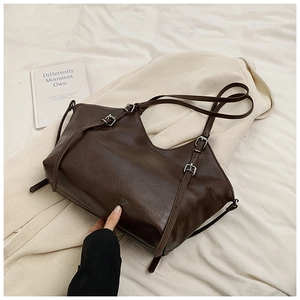 Detailed macro view of dark brown leather tote bag with vintage silver buckles and straps
