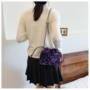 Dettaglio borsa a secchiello con paillettes viola e tracolla indossata da una modella