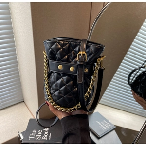 Close-up of black quilted bucket bag featuring gold hardware and elegant chain strap