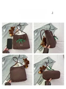 Detail view of brown suede bucket bag with green bow and dachshund plush charm