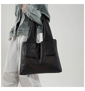 Close-up of black leather tote bag featuring red circular quilting and textured finish