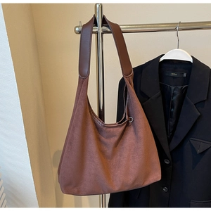 Détail macro du sac à bandoulière en daim marron avec une large sangle en cuir pour l'automne