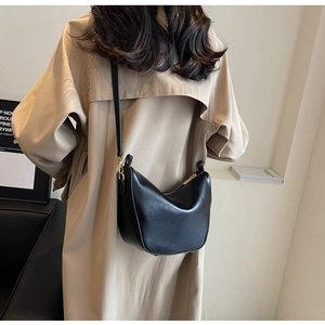 Detailed view of black PU leather crescent hobo bag worn with a stylish khaki trench coat