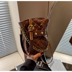 Detail of brown quilted bucket bag with gold chain and refined leather texture