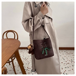 Deep brown faux suede bucket bag with cross-lace detailing and plush bear charm