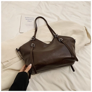 Detail of dark brown tote bag with silver metal buckles on premium leather material