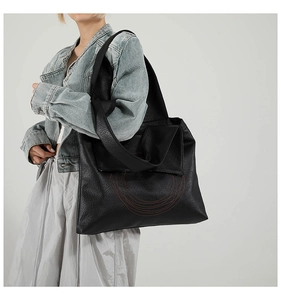 Detail of black pebbled leather tote bag with unique red stitched ring pattern