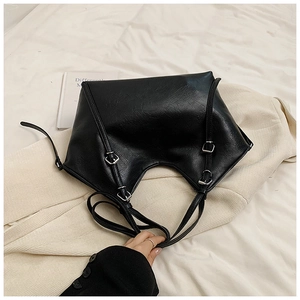 Macro shot of black tote bag featuring fine leather texture and silver metal buckles