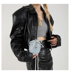 Détail du mini porte-monnaie en denim bleu clair avec nœud perlé et pendentif cœur