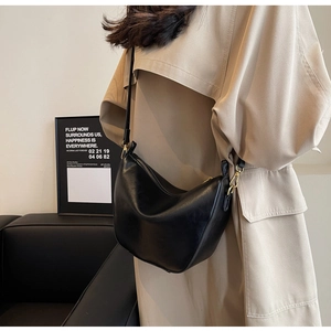 Detail view of a black hobo shoulder bag with golden hardware and smooth leather finish