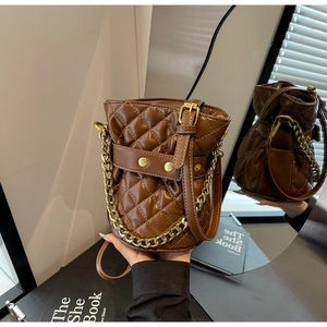 Detail of brown quilted bucket bag with gold chain strap and elegant stitching