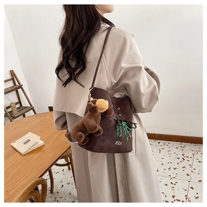 Detail of coffee suede bucket bag with white embroidery and plush puppy keychain