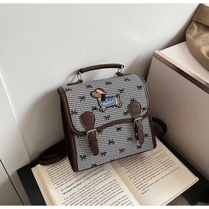 Detail of dachshund embroidery on houndstooth backpack with leather accents