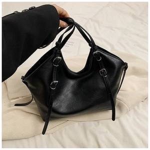 Detail view of black textured leather tote bag with stylish metal buckle decorations