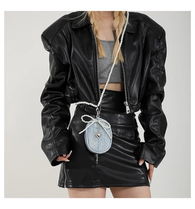Détail d'un mini sac en jean bleu clair avec bandoulière en perles et breloque cœur