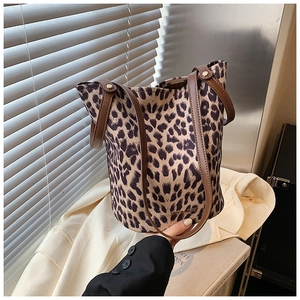 Detail view of leopard print bucket bag with brown faux leather handles and rivet accents