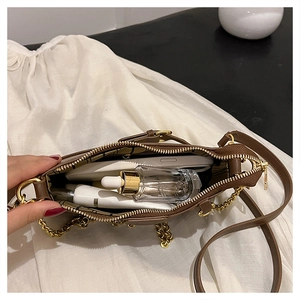 Internal view of brown leather bag showing spacious capacity with items and gold chain detail