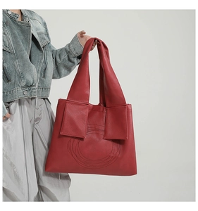 Close-up of red leather tote bag with unique circular embroidery and lychee texture