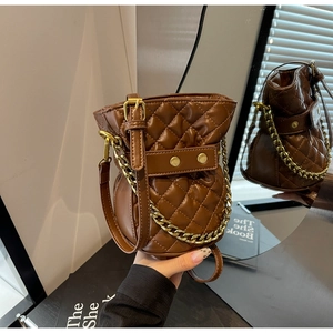 Detailed close-up of brown quilted bucket bag with gold studs and chain through mirror reflection