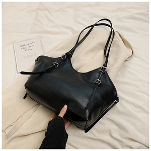 Close-up of black PU leather tote bag texture with silver metal buckle on a bed