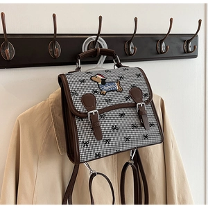 Detail of houndstooth backpack with dachshund embroidery and brown leather trim