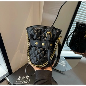 Close-up of black quilted bucket bag featuring gold chain strap and rivet details