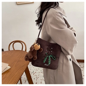 Detail view of brown suede tote bag with metal eyelets and plush puppy charm