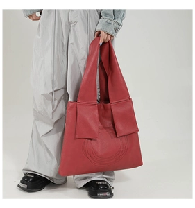 Detail of red large capacity tote bag with modern ring stitching and wide shoulder strap