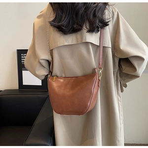 Rear view of a model wearing a brown leather crescent bucket bag with gold hardware