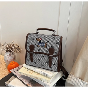 Detail of vintage houndstooth backpack with embroidered dachshund and leather straps