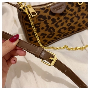 Detailed close-up of leopard print bag strap with golden hardware and leather stitching