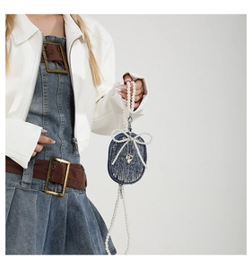 Détail du mini porte-monnaie en jean bleu avec nœud en perles et breloque cœur