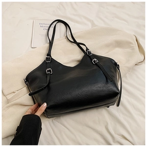 Detail of black faux leather tote bag showing textured surface and silver adjustable buckles