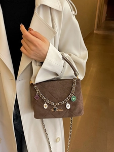 Elegant dark brown quilted crossbody bag with heart charms and gold chain shoulder strap