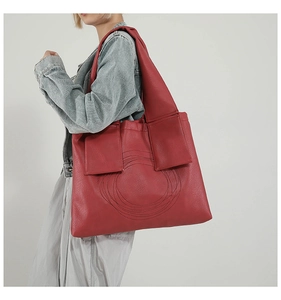 Detail view of large red tote bag with concentric circle stitching and wide shoulder strap