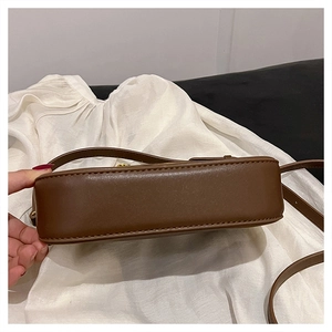 Close-up of the brown leather shoulder bag showing bottom stitching and gold metal hardware