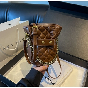 Detailed view of dark brown quilted bucket bag with gold chain strap and luxury textures
