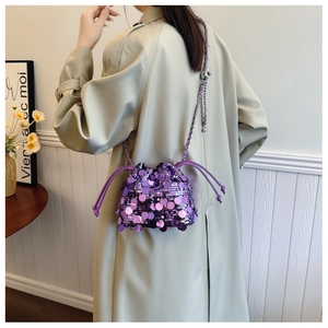 Primo piano di una borsa a secchiello con paillettes viola e tracolla su un trench