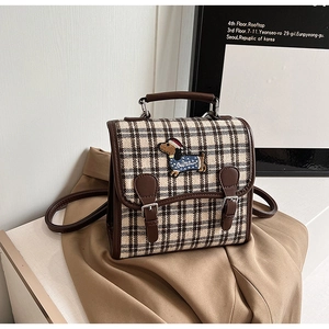 Detail of dog embroidery and leather strap buckles on a plaid vintage backpack
