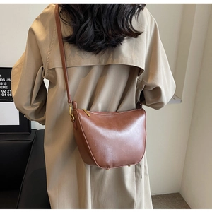 Detailed back view of a brown crescent shoulder bag worn with a stylish beige trench coat