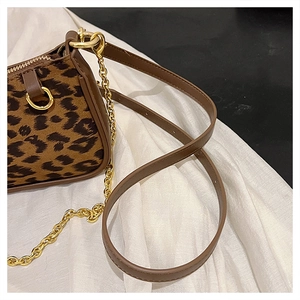 Detailed macro view of leopard print texture with leather strap and gold metal chain