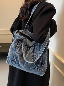 Washed blue denim tote bag with multiple pockets and zipper for casual streetwear style