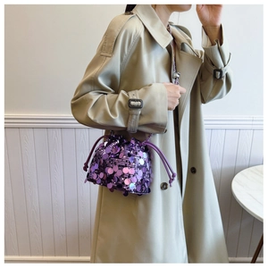 Dettaglio di una borsa a secchiello con paillettes viola e chiusura con coulisse