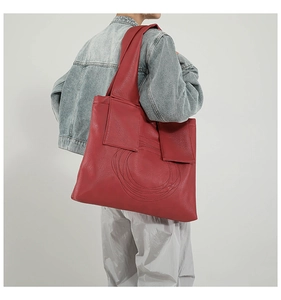 Detailed view of vintage red tote bag with round stitching worn on a denim jacket